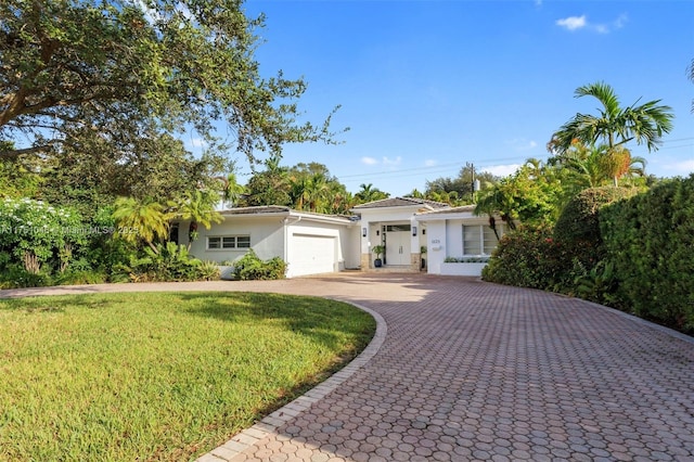 ranch-style house with a garage, a front lawn, decorative driveway, and stucco siding