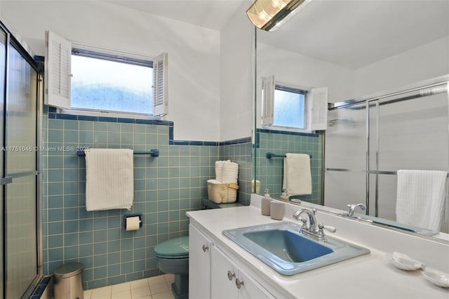 full bath featuring a shower with shower door, vanity, tile walls, and tile patterned floors