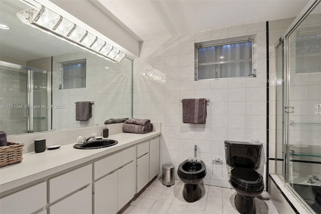 bathroom featuring toilet, tile patterned flooring, a shower stall, a bidet, and tile walls