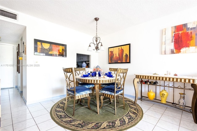 tiled dining area featuring visible vents, a textured ceiling, and an inviting chandelier