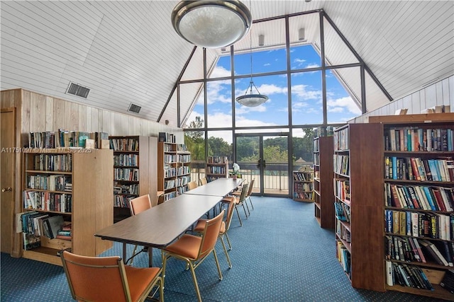 interior space featuring a wall of windows, vaulted ceiling, and wood walls