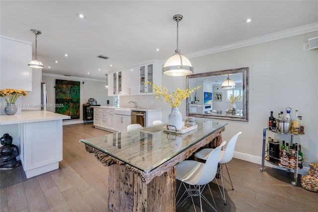 kitchen with white cabinetry, glass insert cabinets, stainless steel dishwasher, and decorative light fixtures