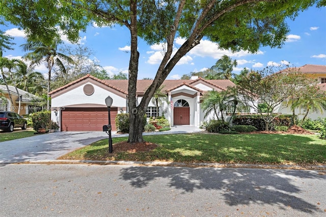 mediterranean / spanish house with driveway, a tile roof, an attached garage, a front lawn, and stucco siding