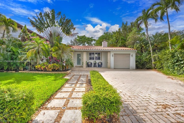 view of front facade with decorative driveway, a chimney, stucco siding, an attached garage, and a front lawn