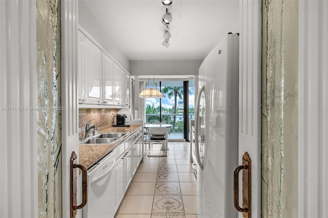 kitchen featuring white appliances, light tile patterned floors, white cabinets, and a sink