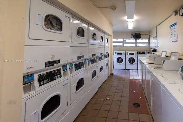 shared laundry area featuring stacked washer / dryer, washing machine and dryer, and dark tile patterned flooring