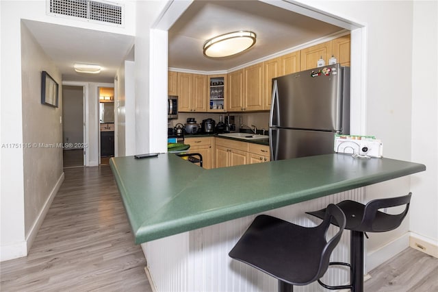 kitchen with dark countertops, glass insert cabinets, a kitchen breakfast bar, a peninsula, and stainless steel appliances