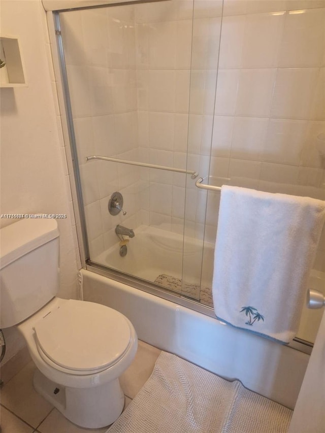 bathroom featuring enclosed tub / shower combo, toilet, and tile patterned floors