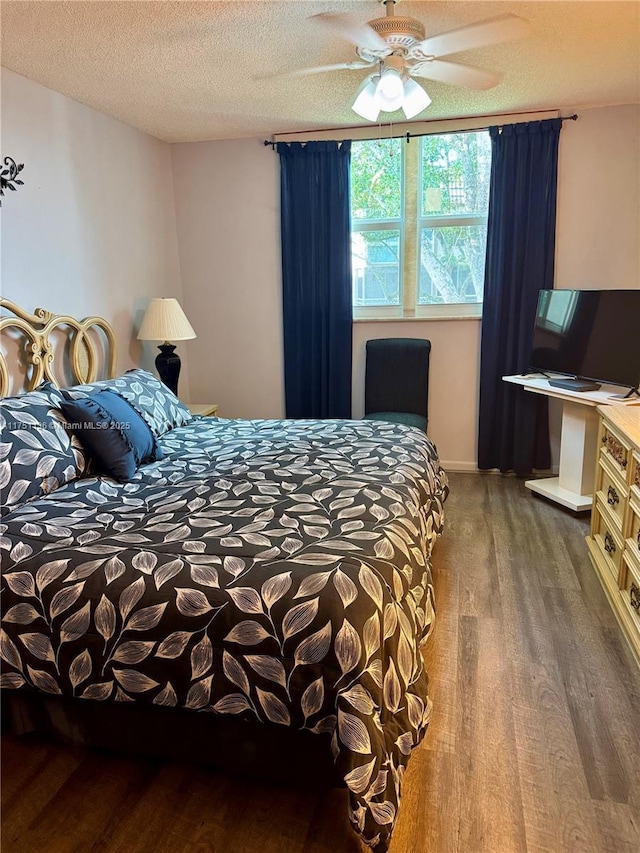 bedroom with a ceiling fan, a textured ceiling, baseboards, and wood finished floors