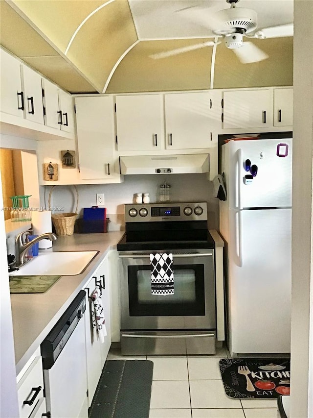 kitchen featuring white appliances, white cabinets, light countertops, under cabinet range hood, and a sink