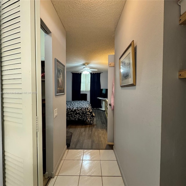 9200 Lime Bay Blvd Unit 212, Tamarac, FL 33321 - hall featuring baseboards, a textured ceiling, and light tile patterned floors