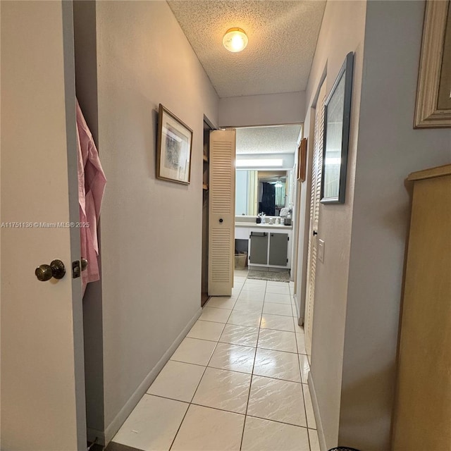 9200 Lime Bay Blvd Unit 212, Tamarac, FL 33321 - hallway featuring baseboards, a textured ceiling, and light tile patterned floors
