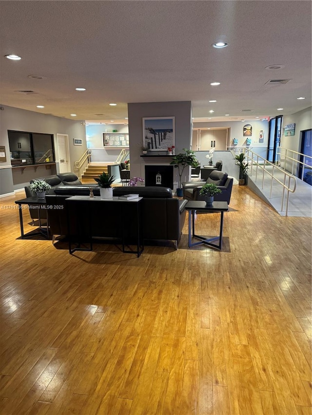 living room featuring light wood-style flooring, stairway, a textured ceiling, and recessed lighting