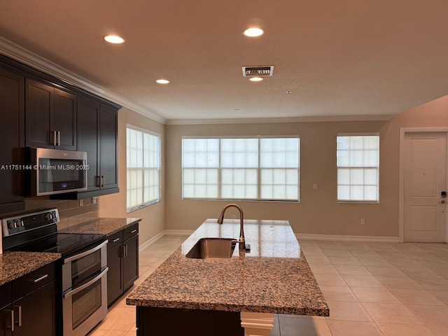 kitchen with crown molding, appliances with stainless steel finishes, stone countertops, a kitchen island with sink, and a sink