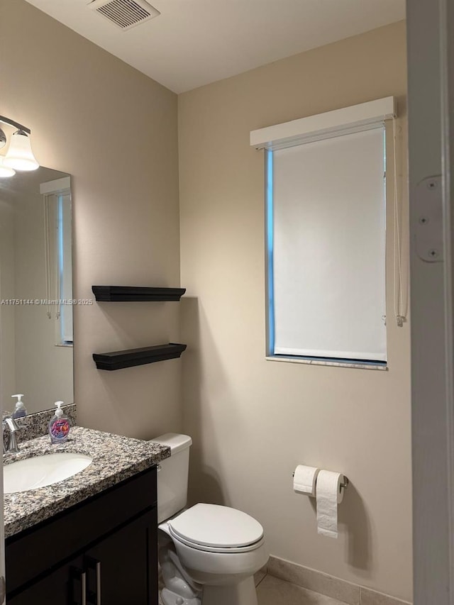 half bathroom featuring visible vents, baseboards, toilet, tile patterned flooring, and vanity