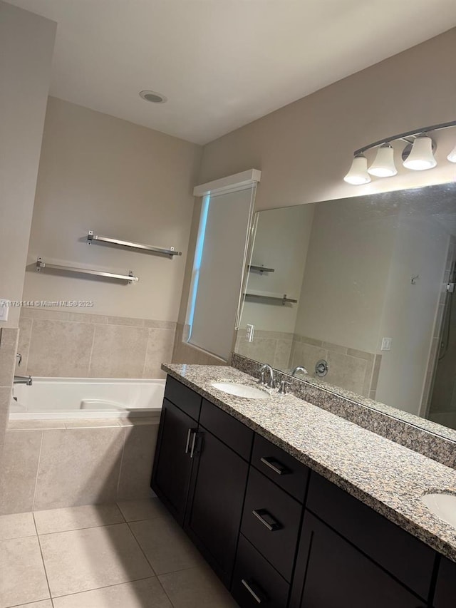 full bathroom featuring double vanity, tile patterned flooring, a sink, and a bath