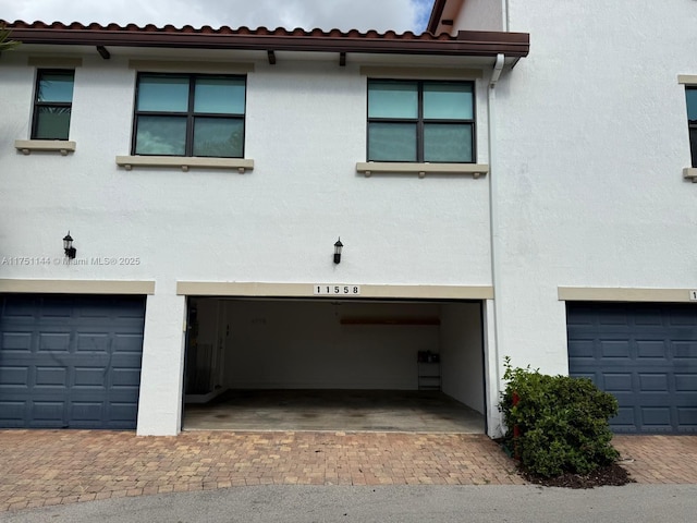 view of front of house featuring a garage, a tile roof, and stucco siding