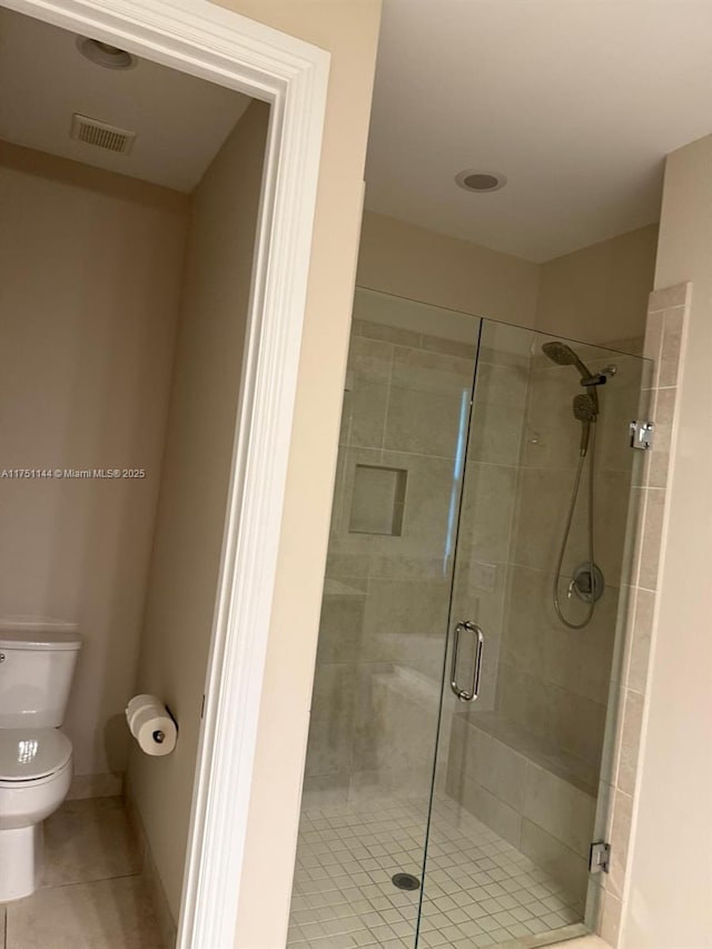 full bathroom featuring tile patterned flooring, toilet, visible vents, baseboards, and a shower stall