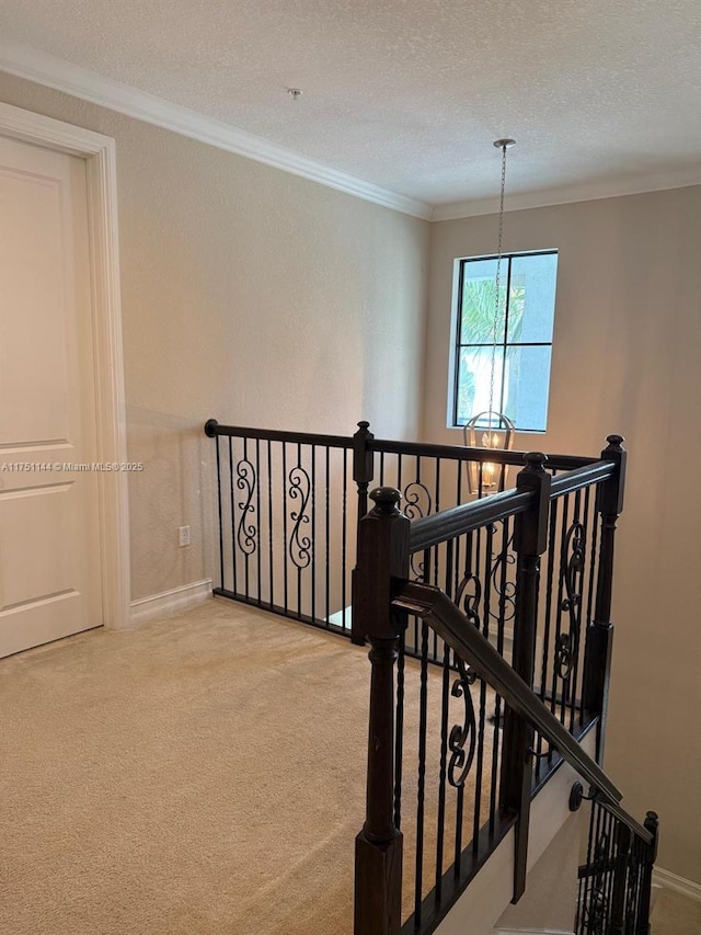 stairway with a textured ceiling, ornamental molding, carpet flooring, and baseboards