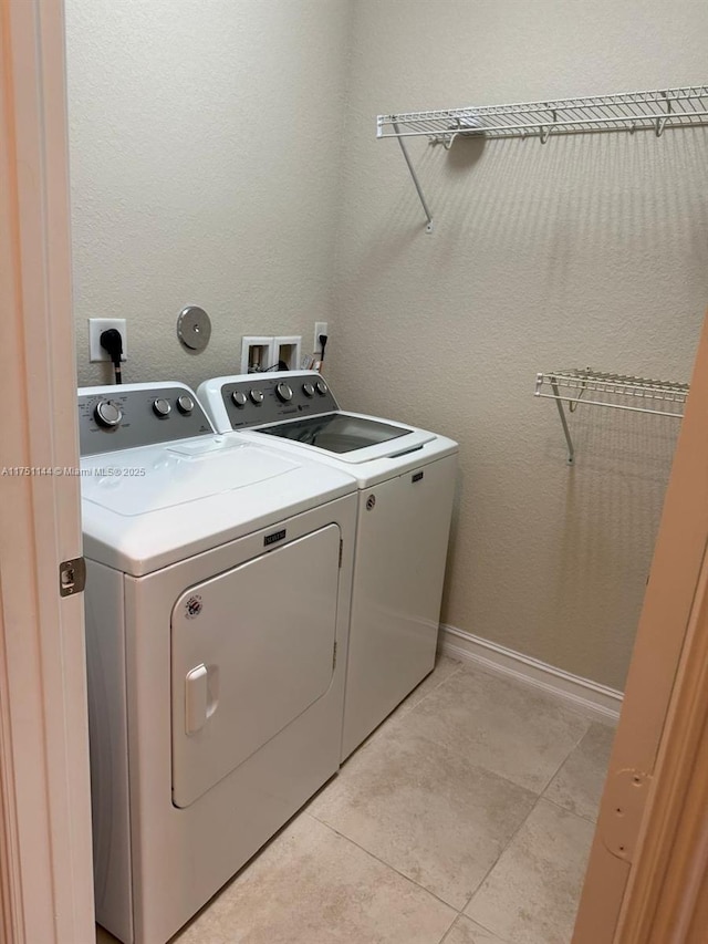 laundry room featuring light tile patterned floors, laundry area, washing machine and dryer, and baseboards