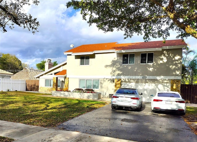 view of front facade with a chimney, fence, a garage, driveway, and a front lawn