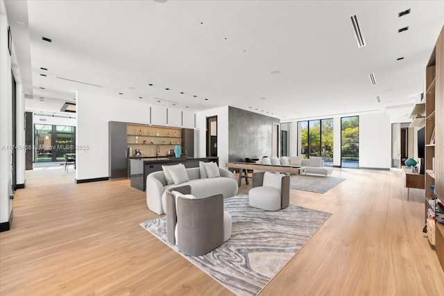 living area with light wood-type flooring, expansive windows, baseboards, and a wealth of natural light
