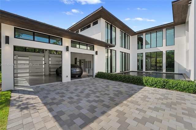 rear view of house featuring stucco siding, driveway, and a garage