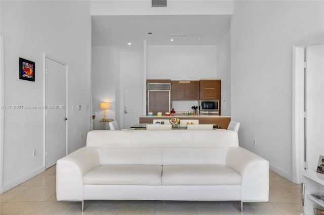 living room featuring rail lighting, a high ceiling, visible vents, and light tile patterned flooring