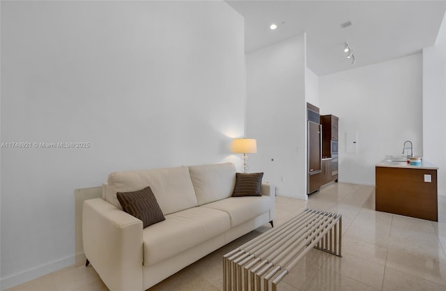 living area with light tile patterned floors, a high ceiling, recessed lighting, and baseboards