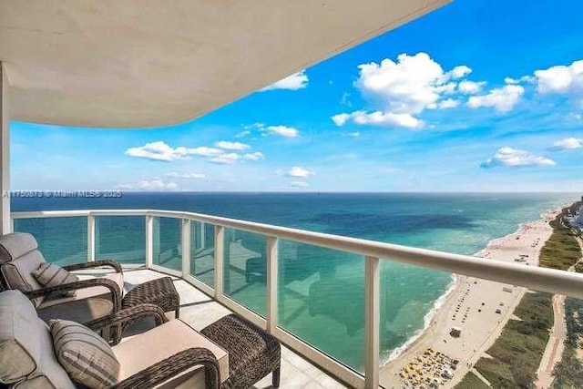 balcony with a water view and a view of the beach