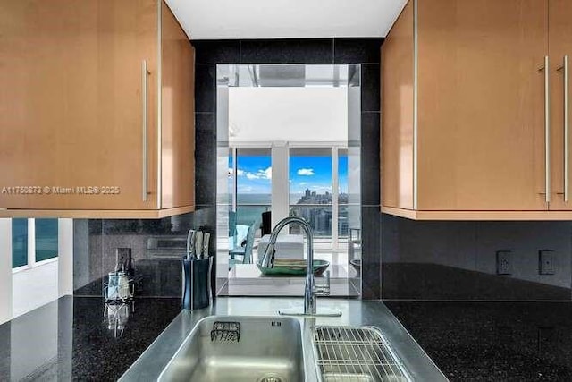 kitchen with backsplash, dark stone countertops, and a sink