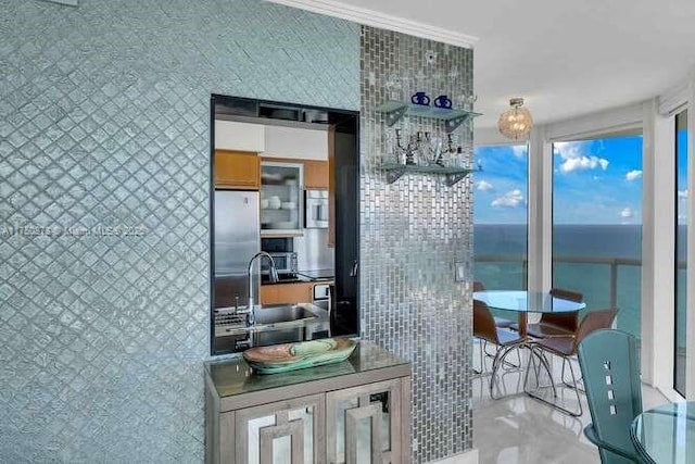 interior space with a water view, a sink, open shelves, and stainless steel refrigerator