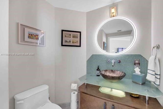 bathroom with toilet, vanity, and decorative backsplash