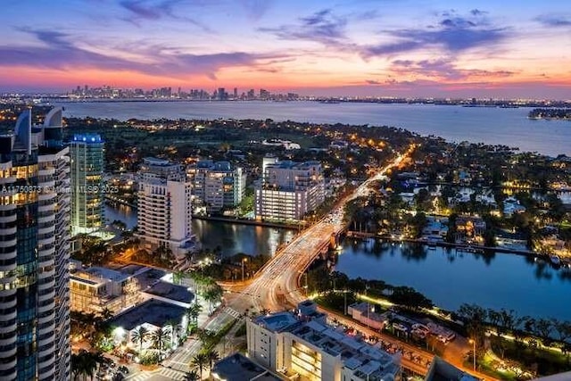 aerial view at dusk featuring a view of city and a water view