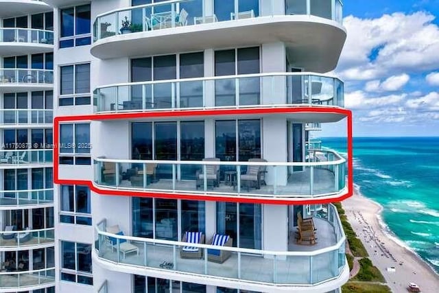 view of building exterior with a water view and a beach view