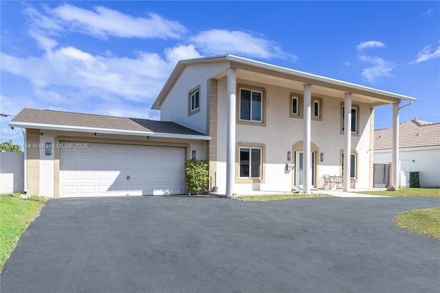 greek revival inspired property with driveway, an attached garage, and stucco siding