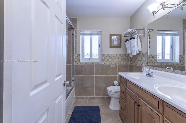 full bathroom with a healthy amount of sunlight, tile walls, toilet, and a sink