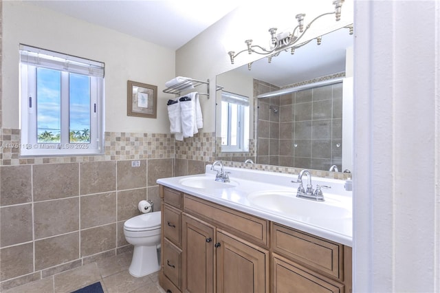 bathroom featuring a tile shower, a sink, tile walls, and toilet