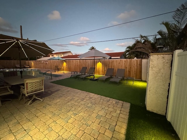 patio terrace at dusk with a fenced backyard and outdoor dining space