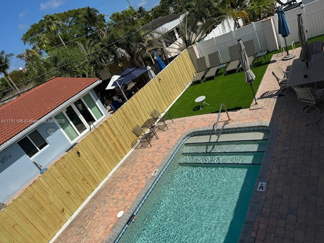 pool with a lawn, a patio area, and fence