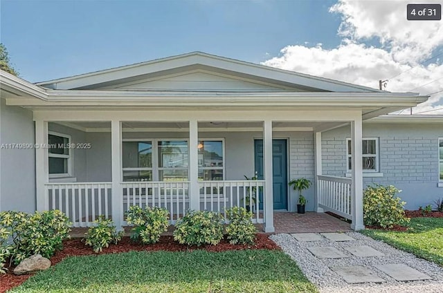 view of exterior entry featuring a porch and brick siding