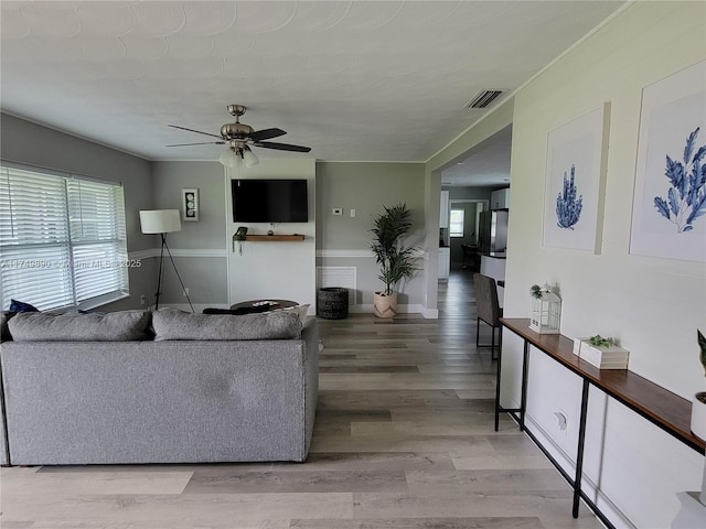 living room featuring wood finished floors, visible vents, and a ceiling fan