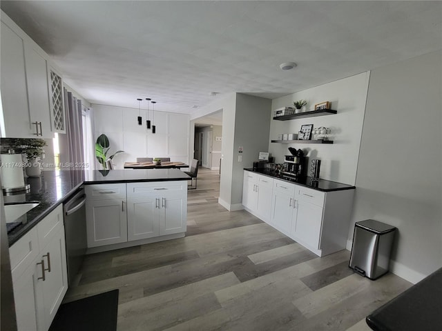 kitchen featuring a peninsula, dark countertops, white cabinetry, and dishwasher