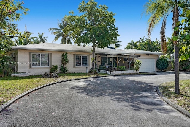 ranch-style house with brick siding, a front lawn, an attached garage, and aphalt driveway