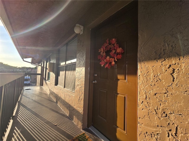 view of exterior entry featuring a balcony and stucco siding