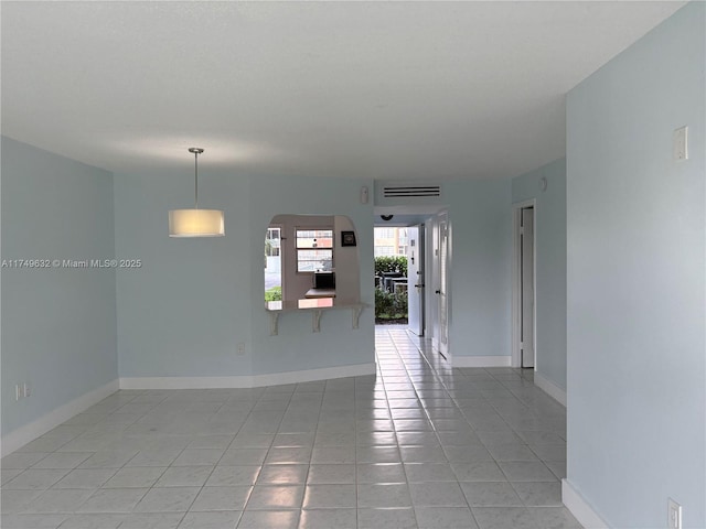 unfurnished room featuring arched walkways, baseboards, and light tile patterned floors