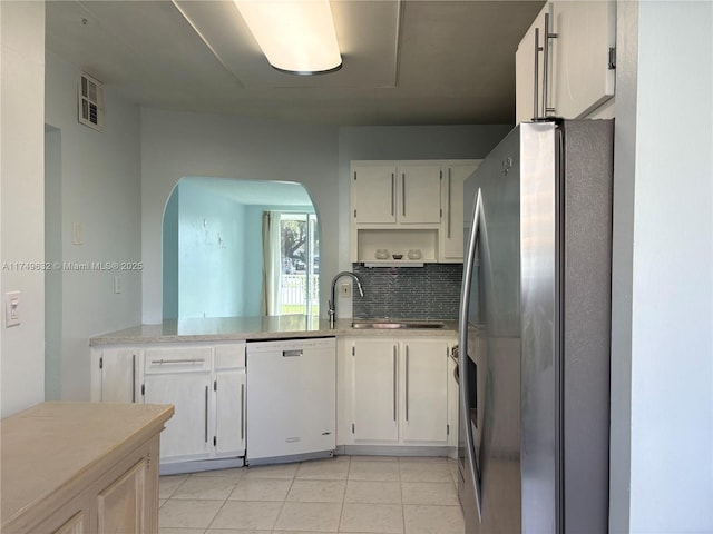 kitchen with decorative backsplash, freestanding refrigerator, white dishwasher, light countertops, and a sink