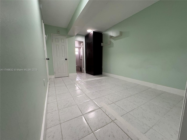 spare room featuring light tile patterned floors and baseboards