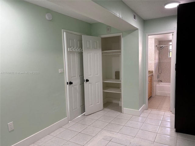 unfurnished bedroom with a closet, light tile patterned flooring, visible vents, and baseboards