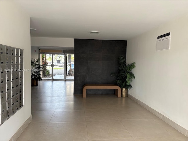 hall with light tile patterned floors, mail area, and baseboards